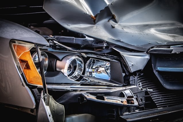 Close up image of a car's damaged front headlight and hood.