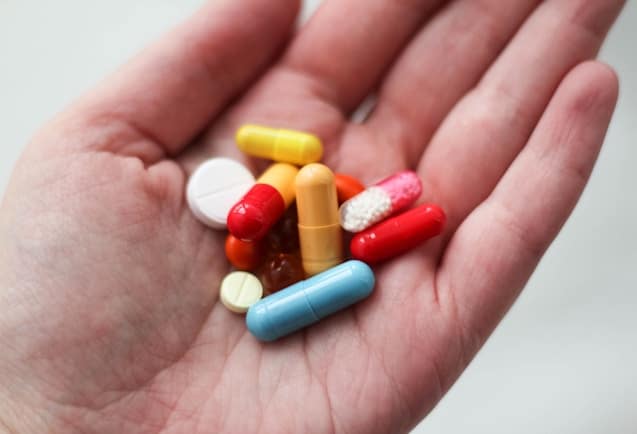 An open hand is seen with colorful pills in the palm.