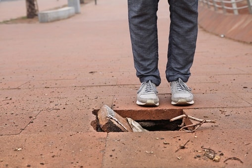 Damaged pavement, dangerous sidewalk.